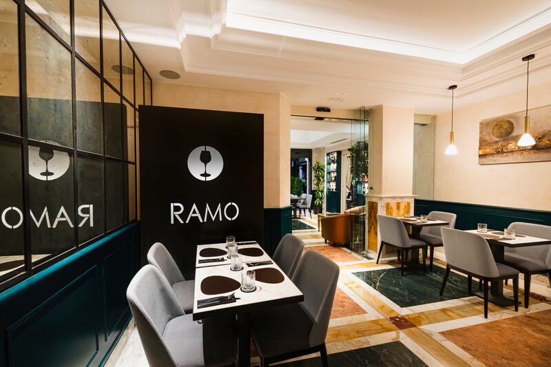Il Ramo Bistrot: tavoli apparecchiati, la parete con il logo e il pavimento in marmo